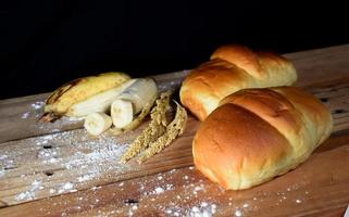 a closeup shot of delicious homemade banana bread with flour on a black background with blurred shadow images. photo