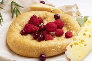 lavash con rojo bayas y un pedazo de queso. horneado redondo bollo para desayuno. foto