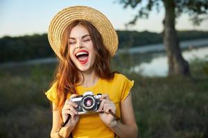 Emotional woman photographer with open mouth wearing hat red lips camera nature