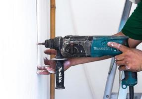 close up of electric drill making hole in a wall, repair, building and home concept photo