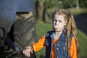 A little girl in bright clothes blew out a bubble of gum. photo