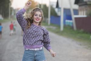 contento joven niña bailando en el calle.hermosa niña con largo pelo elevado su mano arriba. foto