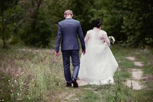 The bride and groom leave along the forest path. photo