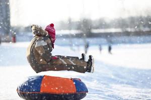 pequeño niño en un trineo. niño en un invierno día. un chico es montando en un nieve deslizar. foto