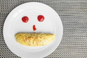 yellow omlette serves with  ketchup on white plate photo