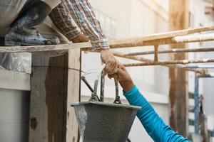 builder contractor man transfers mix fresh concrete in industry work project, prepare to pour wet liquid material into the form in construction site as professional employment photo