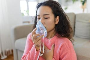 enfermo asiático mujer haciendo inhalación, medicina es el mejor medicamento. enfermo mujer vistiendo un oxígeno máscara y pasando tratamiento para COVID-19. mujer con un inhalador foto