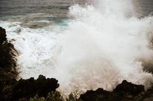 enorme mar olas estrellarse en el rocoso apuntalar foto