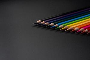 Set of colored pencils, row of wooden colored pencils on black background. colored pencils for drawing. pencils arranged in rainbow colors, colorful, copy space. photo