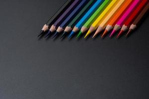 Set of colored pencils, row of wooden colored pencils on black background. colored pencils for drawing. pencils arranged in rainbow colors, colorful, copy space. photo