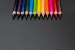 Set of colored pencils, row of wooden colored pencils on black background. colored pencils for drawing. pencils arranged in rainbow colors, colorful, copy space. photo