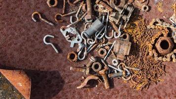 Rusted screws, nuts and bolts in a rusty iron case, rusty nails, rusty chains, These rusty metal parts appear on the surface, rust background. photo