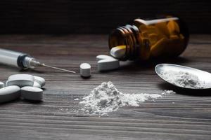 Drugs set - powder and pills and syringe on wooden background photo