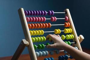 Abacus with colorful beads on blue background, close up, Counts kids learning, kids math class concept, with counting child's hands photo