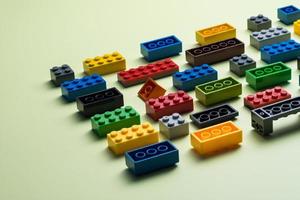 various colorful plastic toy bricks stackable blocks on yellow panoramic background, childhood education construction concept, photo