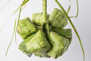 Ketupat lebaran is a typical Indonesian food during the festive season of Ketupat, Eid al Fitr, Eid al Adha, natural rice wrap made from young coconut leaves on a white background, empty space photo