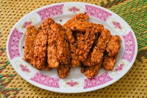 Tempe goreng, Indonesian cuisine, Indonesian Fried Tempeh made from soybeans, Food A simple dish that is often made at home. Indonesian Street Food. served on a plate photo