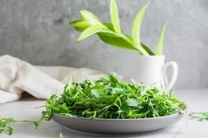 Fresco hojas de Rúcula en un plato en el mesa. orgánico dieta vegetariano alimento. estilo de vida. Copiar espacio foto