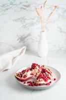 A whole ripe pomegranate divided into pieces on a plate on a light table. Organic natural food. Lifestyle. Vertical view photo