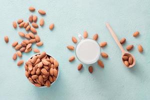 Peeled almonds in a bowl and almond milk in a glass on a light background. Alternative nutrition, source of vitamins. Top view photo