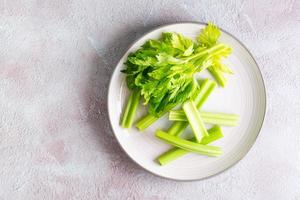 Sliced fresh celery stalk with leaves on a plate on the table ready to eat. Vegetarian food. Top view. Copy sace photo