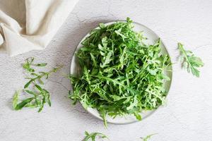 Fresh leaves of arugula on a plate on the table. Organic diet vegetarian food. Lifestyle. Top view photo