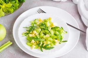 Ready to eat fresh salad of celery, green apple, arugula and sesame seeds on plates on the table. Vegetarian diet. Close-up photo