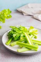 Sliced fresh celery stalk with leaves on a plate on the table ready to eat. Vegetarian food. Vertical view photo