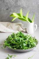 Fresco hojas de Rúcula en un plato en el mesa. orgánico dieta vegetariano alimento. estilo de vida. vertical ver foto
