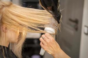 Hand drying hair of woman photo