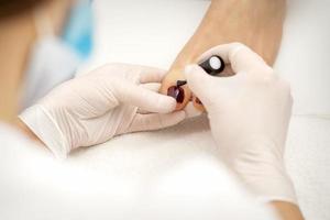 Pedicurist applying burgundy nail polish photo