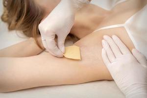 Beautician waxing young female armpit photo