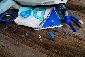 mochila con colegio suministros y en de madera antecedentes. ver desde arriba. espalda a el colegio concepto. foto