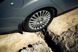 Car wheel stuck in a pit. Big ditch on a rural road.Side view photo