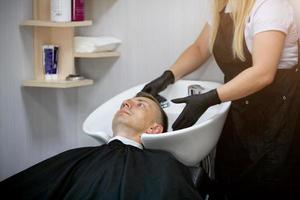 Hairdresser hands in rubber gloves washes shampoo the head  man. photo