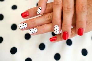 Female hands with a beautiful manicure, on polka dots background. photo