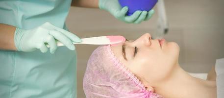 Hand applying alginate mask on face photo