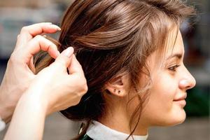 Hairstylist styling hair of woman photo