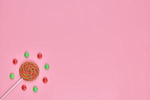 piruleta dulce y caramelo sobre fondo rosa foto