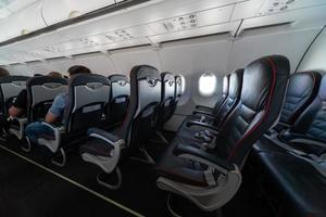 Airplane cabin seats with passengers. Economy class of new cheapest low-cost airlines without delay or cancellation of flight. Travel trip to another country. photo