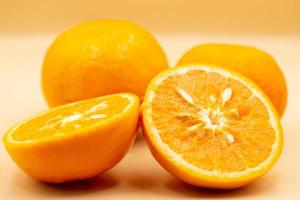 Oranges on pink background. One orange is cut in half, the other is whole. photo