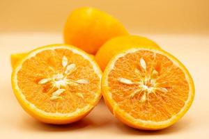 Oranges on pink background. One orange is cut in half, the other is whole. photo