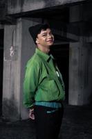 an Asian man smiles while wearing a green parachute jacket and black pants photo