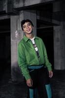 an Asian man smiles while wearing a green parachute jacket and black pants photo