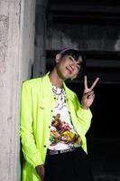 an asian man in a lime colored jacket leaning against a disused building pillar looking very handsome photo