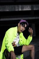 an asian man in a green jacket posing and sitting very casually photo