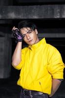 un asiático hombre con pulcro negro pelo vistiendo un amarillo chaqueta y pantalones mientras posando foto
