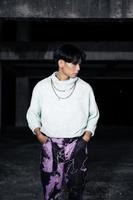 an asian man posing in a white sweater and a chain necklace around his neck photo