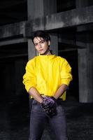 un asiático hombre con pulcro negro pelo vistiendo un amarillo chaqueta y pantalones mientras posando foto