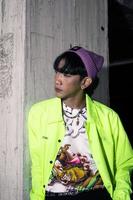 an asian man in a lime colored jacket leaning against a disused building pillar looking very handsome photo